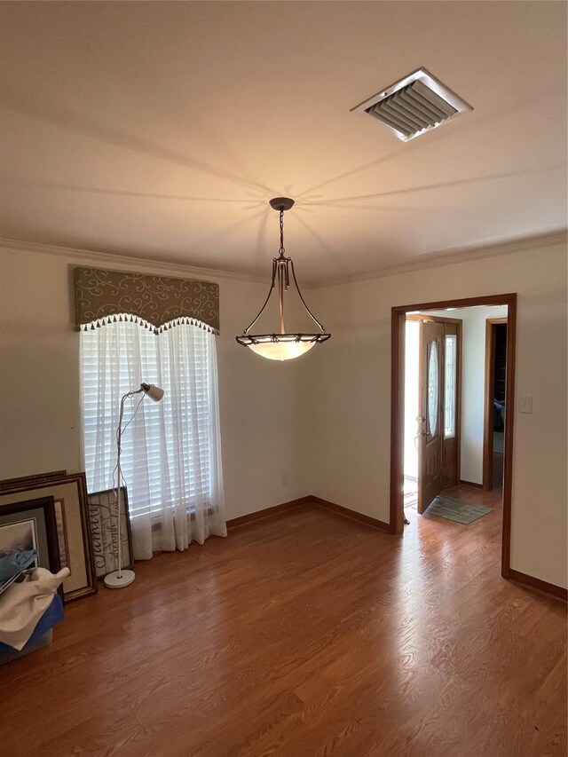 unfurnished dining area with wood finished floors, visible vents, and crown molding