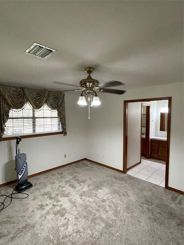 empty room with light carpet, baseboards, visible vents, a ceiling fan, and light tile patterned flooring