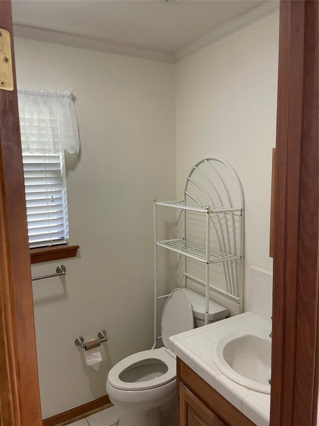 half bathroom featuring ornamental molding, tile patterned flooring, vanity, and toilet