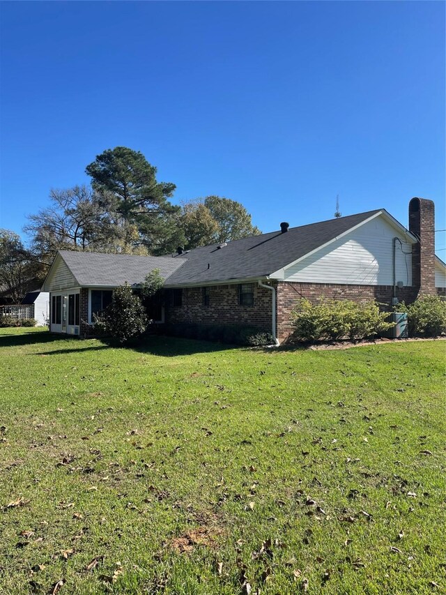 view of side of home featuring a lawn and brick siding