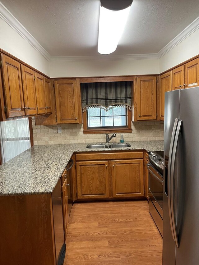 kitchen with appliances with stainless steel finishes, brown cabinetry, and a sink