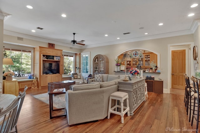 living room with light hardwood / wood-style flooring, a wealth of natural light, ornamental molding, and ceiling fan