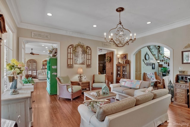 living room featuring ceiling fan with notable chandelier, light wood-type flooring, and ornamental molding