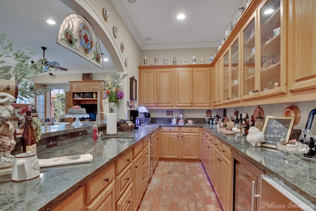 kitchen featuring crown molding, sink, beverage cooler, and dark stone counters