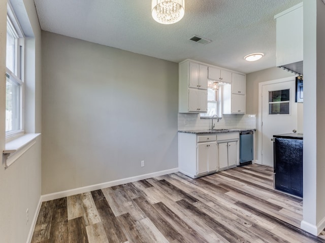 kitchen with backsplash, white cabinets, sink, stainless steel dishwasher, and light wood-type flooring