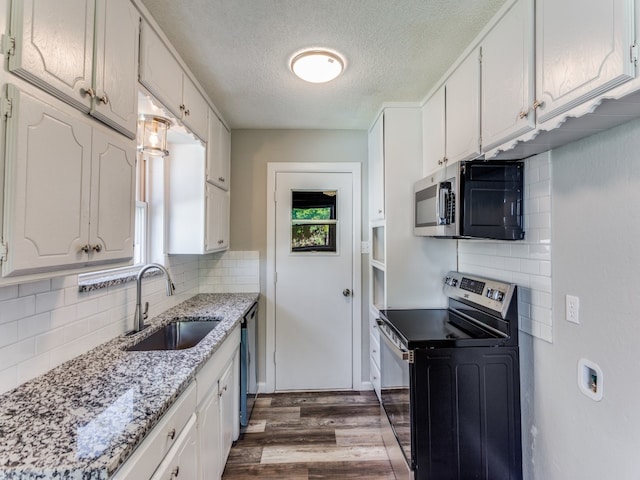 kitchen featuring appliances with stainless steel finishes, a healthy amount of sunlight, sink, dark hardwood / wood-style floors, and white cabinetry