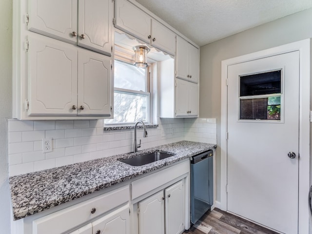 kitchen featuring dark wood-type flooring, white cabinets, sink, stainless steel dishwasher, and light stone countertops