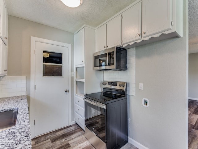 kitchen featuring appliances with stainless steel finishes, backsplash, a textured ceiling, light hardwood / wood-style flooring, and white cabinetry