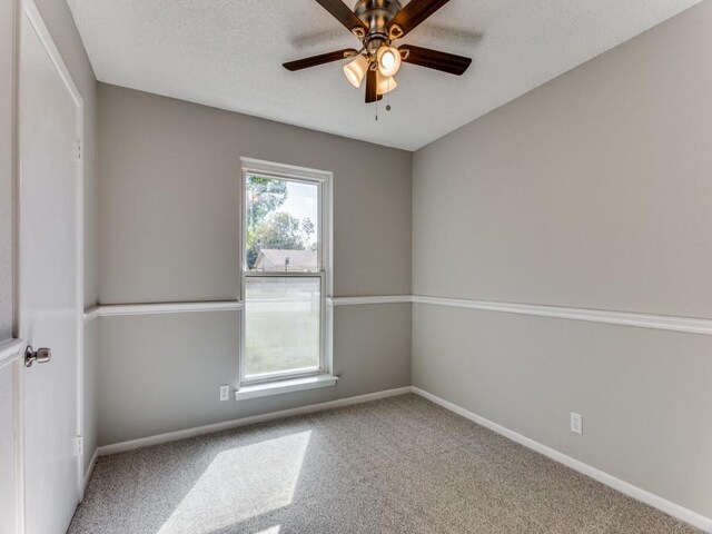 carpeted spare room featuring ceiling fan and a textured ceiling