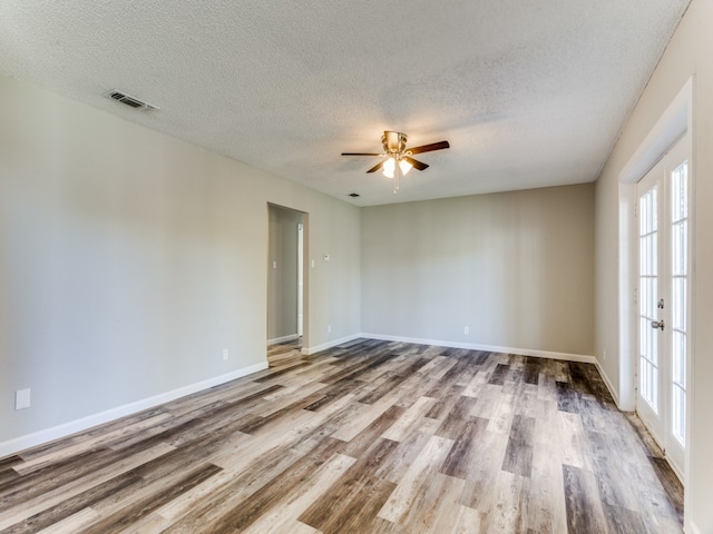 empty room with french doors, a textured ceiling, ceiling fan, and hardwood / wood-style floors