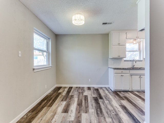 kitchen with decorative backsplash, a textured ceiling, sink, hardwood / wood-style flooring, and white cabinetry