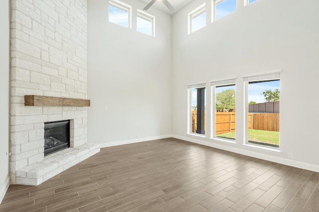 116 Harlan Ct, Aledo, TX 76008 - unfurnished living room featuring a high ceiling, wood finished floors, baseboards, and a stone fireplace