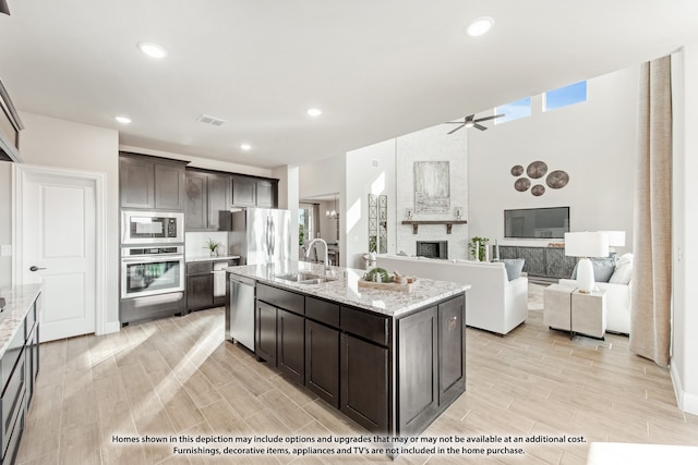 kitchen featuring a kitchen island with sink, sink, ceiling fan, dark brown cabinets, and stainless steel appliances