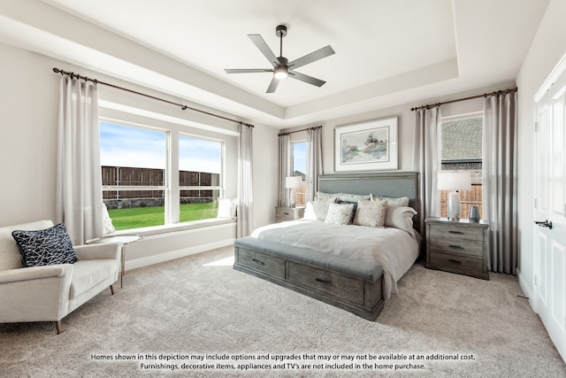 carpeted bedroom featuring a raised ceiling and ceiling fan