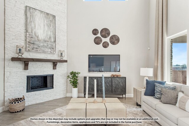 living room with hardwood / wood-style floors, a towering ceiling, and a stone fireplace