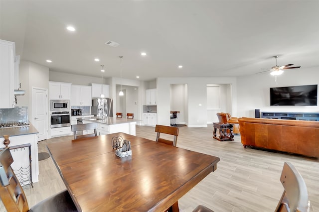 dining room with ceiling fan, light hardwood / wood-style floors, and sink