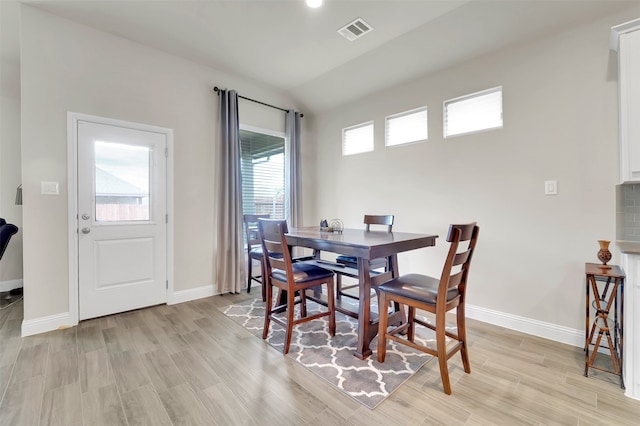 dining room featuring a healthy amount of sunlight, lofted ceiling, and light hardwood / wood-style floors