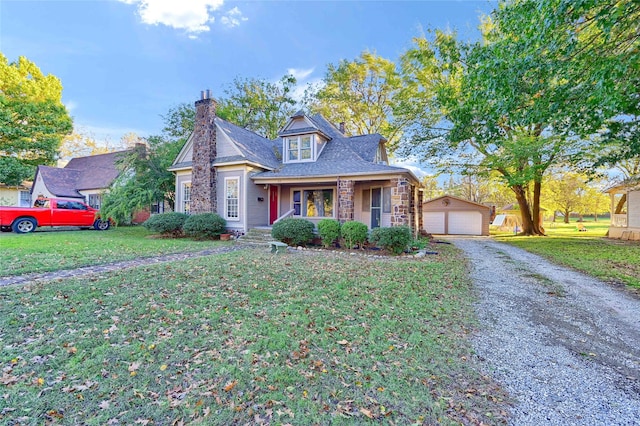 view of front of property featuring a porch, a garage, an outbuilding, and a front lawn