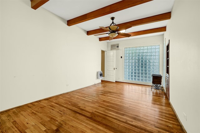 spare room with heating unit, ceiling fan, hardwood / wood-style floors, and beamed ceiling