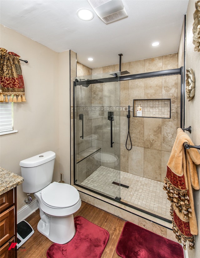 bathroom featuring walk in shower, toilet, vanity, and hardwood / wood-style flooring