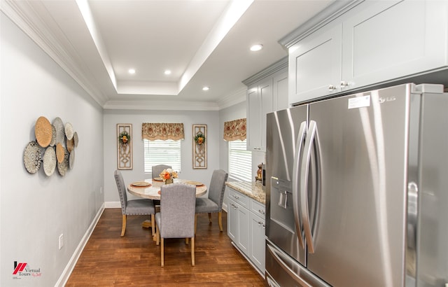 dining room with dark hardwood / wood-style floors, a raised ceiling, and ornamental molding