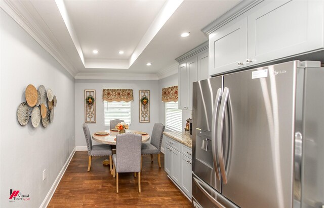 dining room with dark hardwood / wood-style floors, a raised ceiling, and ornamental molding