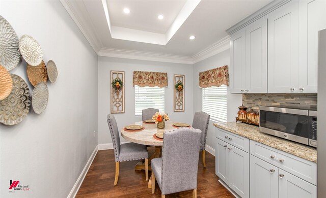 dining room featuring dark hardwood / wood-style flooring, a tray ceiling, and crown molding