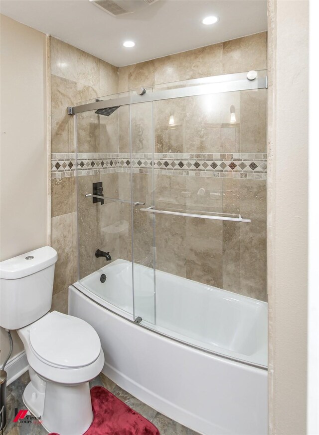 bathroom with toilet and bath / shower combo with glass door