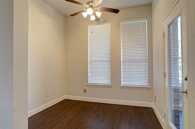 empty room featuring a healthy amount of sunlight, ceiling fan, and dark wood-type flooring