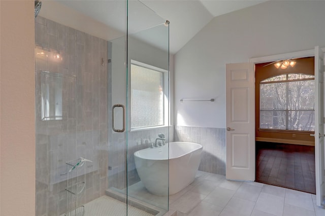 bathroom featuring tile patterned flooring, shower with separate bathtub, tile walls, and vaulted ceiling