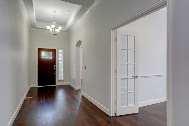 foyer entrance with a raised ceiling, crown molding, a chandelier, and dark hardwood / wood-style floors