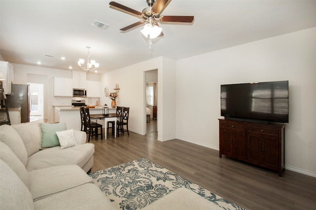 living room with a wealth of natural light, dark wood-type flooring, and ceiling fan with notable chandelier