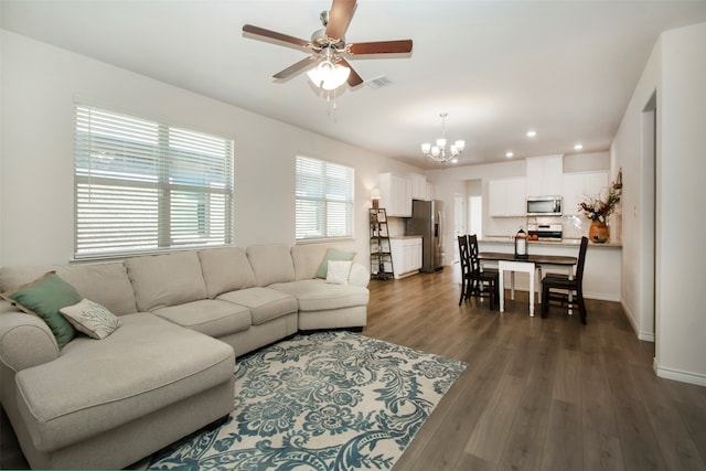 living room featuring ceiling fan with notable chandelier and dark hardwood / wood-style floors