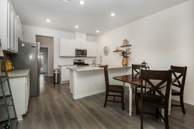 kitchen featuring white cabinetry, stainless steel appliances, light stone counters, dark hardwood / wood-style floors, and decorative backsplash