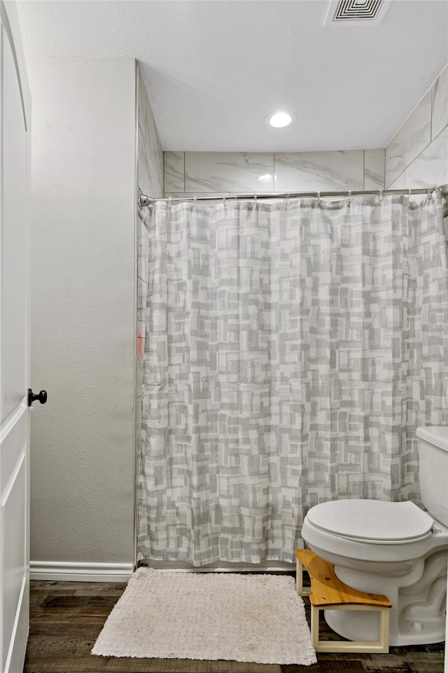 bathroom featuring curtained shower, toilet, and hardwood / wood-style flooring