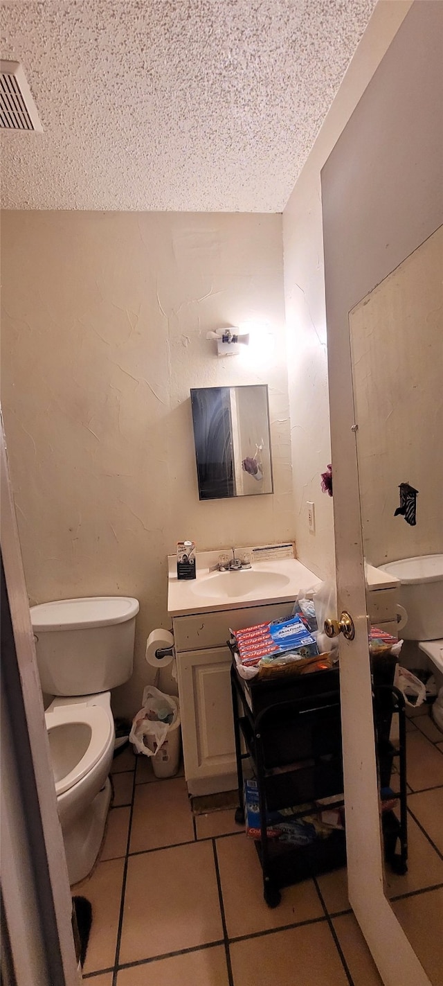 bathroom with tile patterned flooring, a textured ceiling, vanity, and toilet