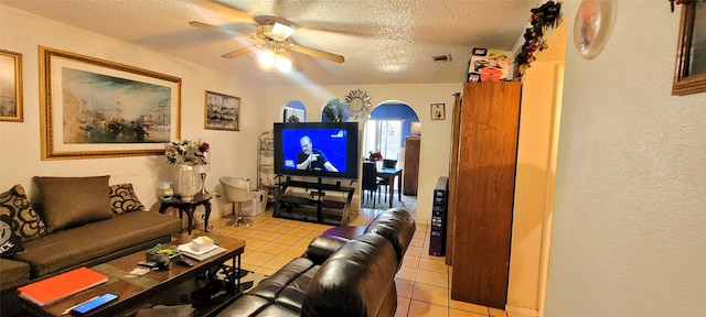 living room with ceiling fan, light tile patterned floors, and a textured ceiling