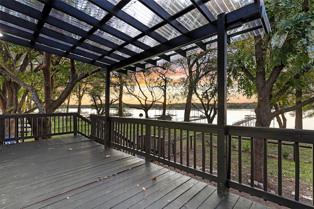 deck at dusk featuring a pergola and a water view