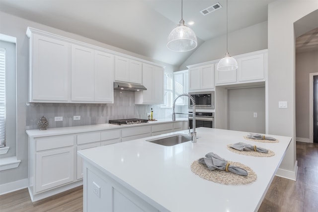 kitchen with white cabinetry, a kitchen island with sink, stainless steel appliances, and lofted ceiling