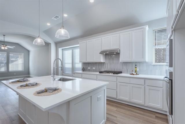 kitchen featuring pendant lighting, lofted ceiling, a center island with sink, sink, and light hardwood / wood-style flooring