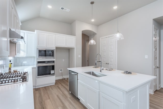 kitchen with appliances with stainless steel finishes, a kitchen island with sink, sink, pendant lighting, and white cabinetry