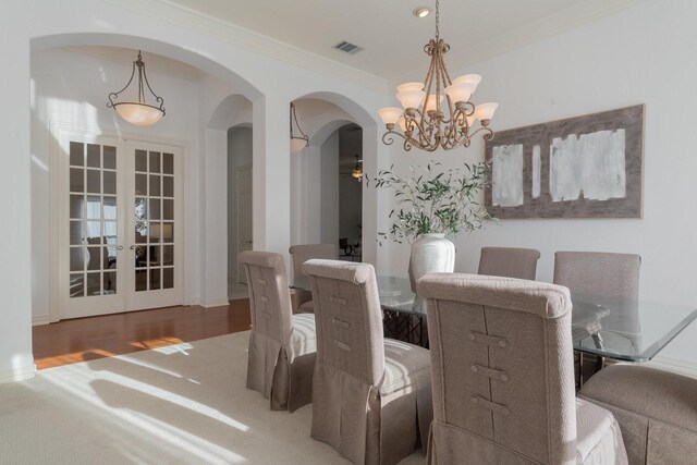 dining space with a notable chandelier, crown molding, and light carpet