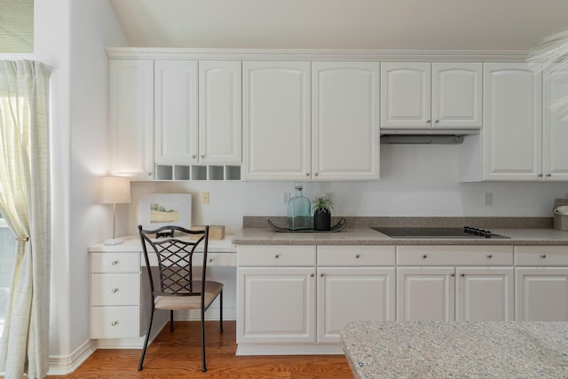 kitchen with light stone counters, white cabinets, black electric stovetop, and light hardwood / wood-style floors