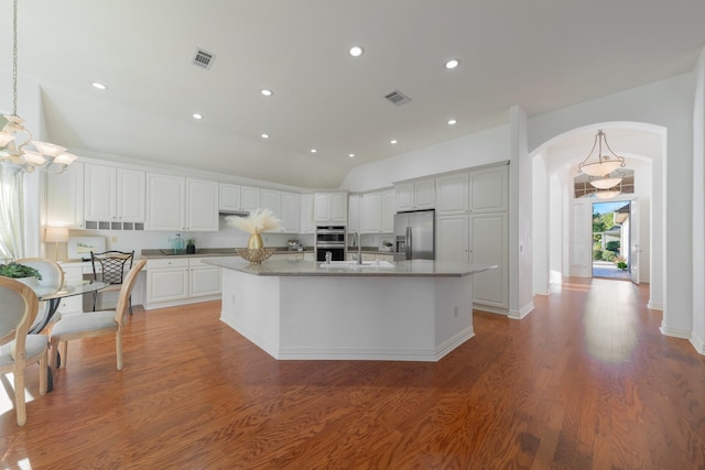 kitchen featuring decorative light fixtures, white cabinets, an island with sink, and appliances with stainless steel finishes