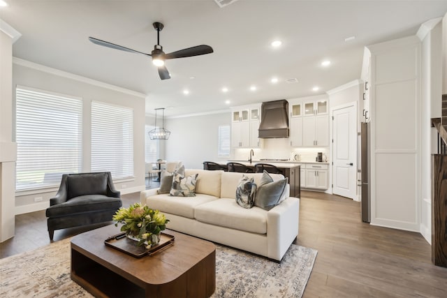 living room with ceiling fan, ornamental molding, and light hardwood / wood-style flooring