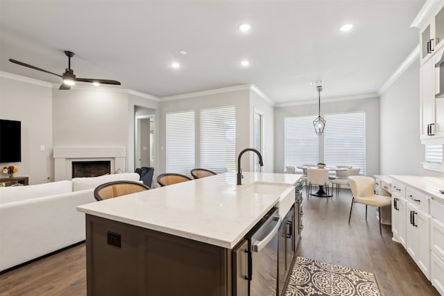 kitchen with pendant lighting, dark hardwood / wood-style flooring, a center island with sink, and crown molding