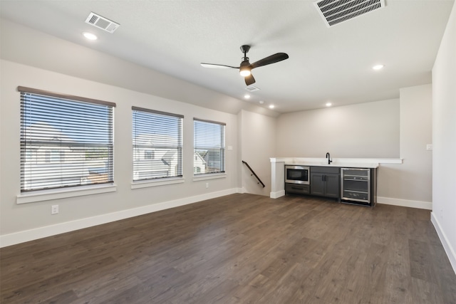 unfurnished living room with wine cooler, ceiling fan, dark hardwood / wood-style flooring, and sink