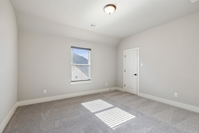 carpeted spare room with vaulted ceiling