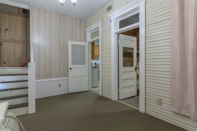 hallway featuring wooden walls and dark colored carpet