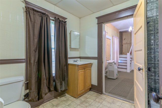 bathroom with vanity, tile walls, and toilet